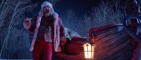 David Harbour dressed as Santa, standing next to his sleigh with a sledgehammer, in Violent Night.