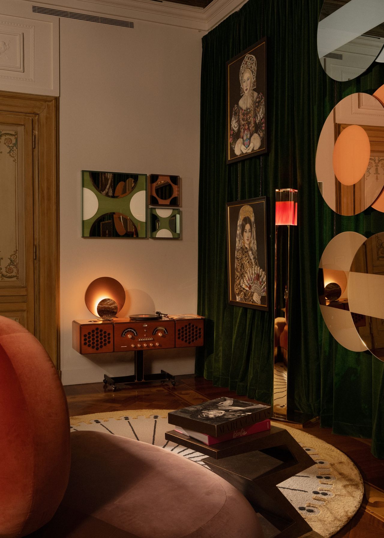 the corner of the entertainment room with mirrored circular decor on the dark green-curtained walls with circulr shapes and decor all around, including the rug and rounded seating