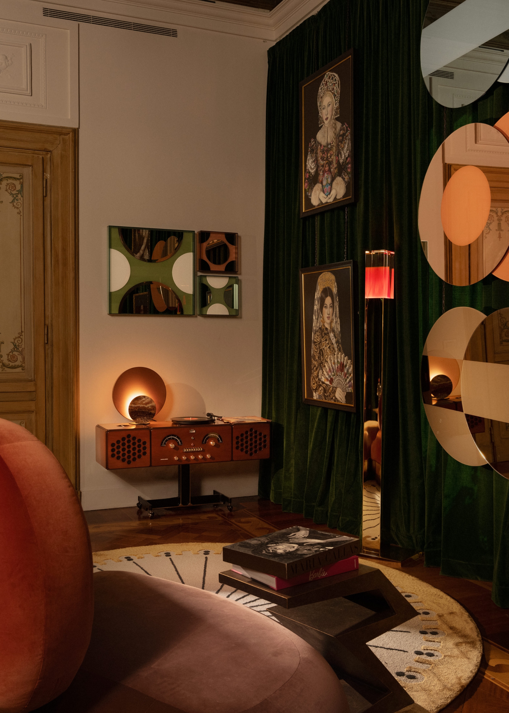 the corner of the entertainment room with mirrored circular decor on the dark green-curtained walls with circulr shapes and decor all around, including the rug and rounded seating