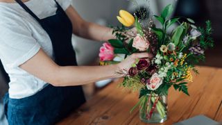 person arranging flowers in vase