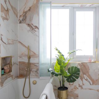 bathroom with marble effect tiles and shower over bath