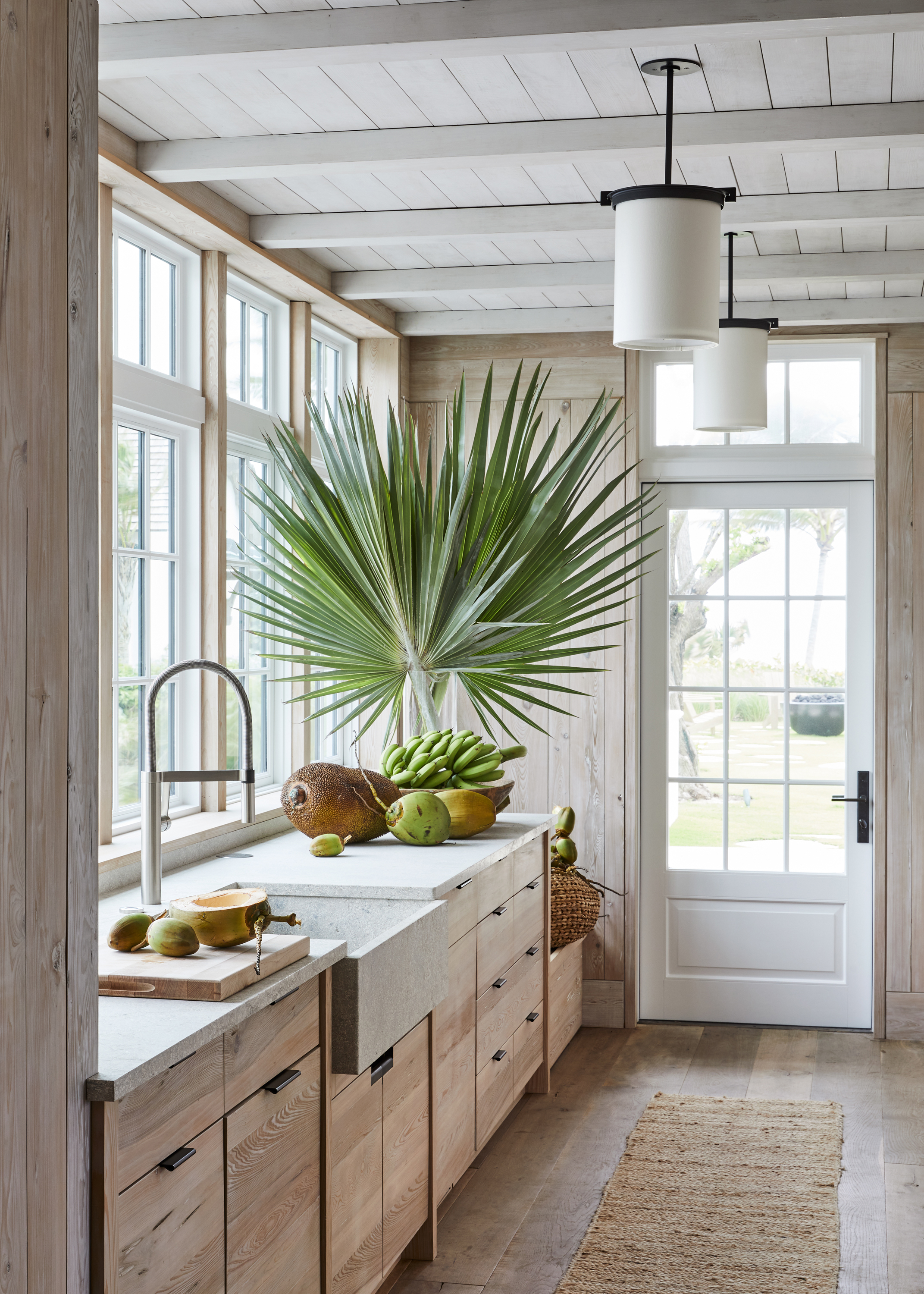 Wooden kitchen with large palm leaf, rattan rug and cement sink