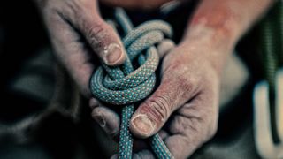 Close up of chalky hands tying a climbing rope in a knot