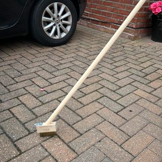 Newman and Cole Long Handle Weed Brush sweeping away weeds from patio driveway