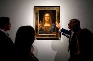 Christie's employees pose in front of a painting entitled "Salvator Mundi" by Leonardo da Vinci at Christie's auction house in central London on October 22, 2017.