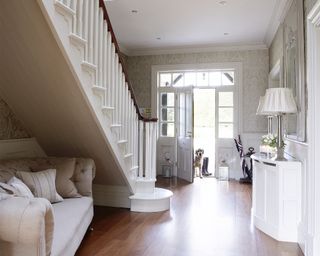Cream traditional hallway idea with sofa under the stairs and dog in porch