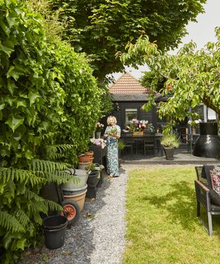 woman standing in a garden makeover with a lawn and gravel path