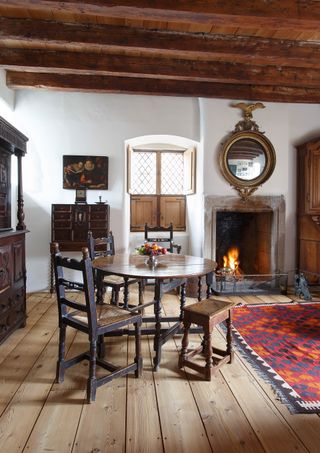 Dining table and chairs in room with fireplace, wood floor and rug