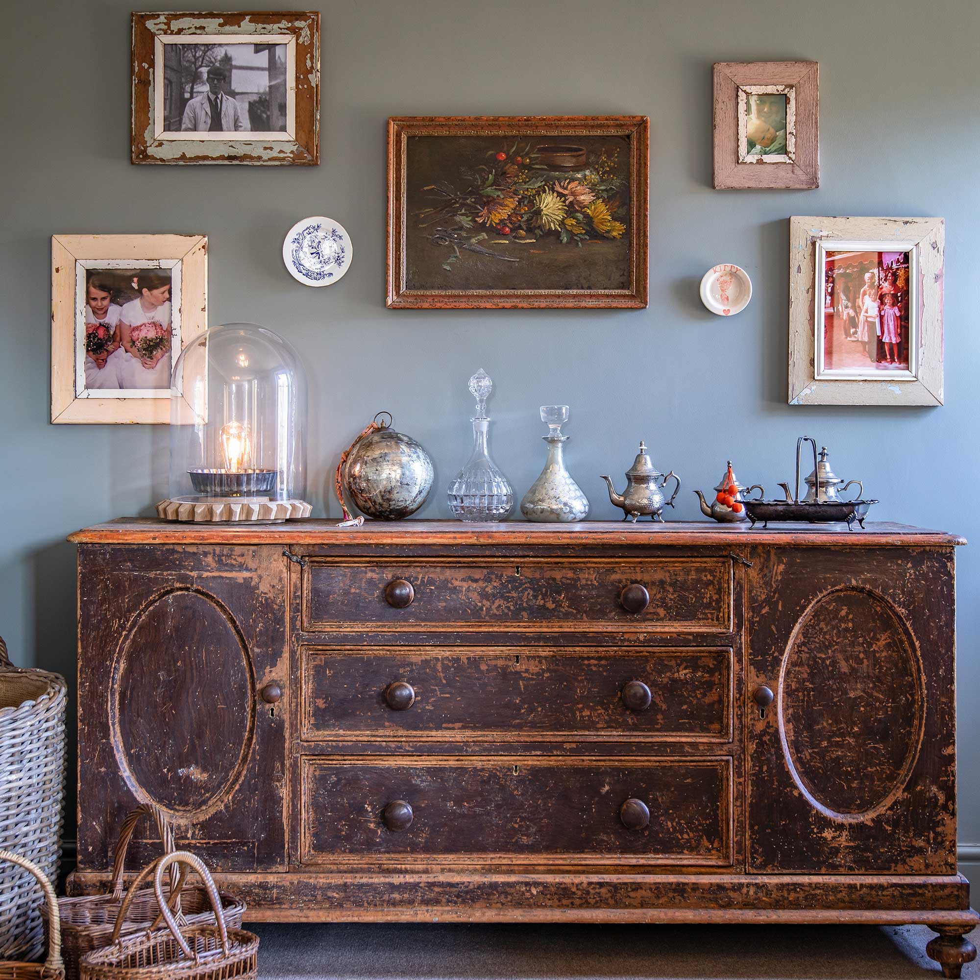 Vintage sideboard with antique and vintage decanters, tea pots and mixed artwork above