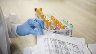 Lab technician with blood samples and medical chart.
