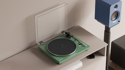 A green Kanto Audio Obi3 turntable on a light-coloured shelf next to a blue Kanto wireless speaker