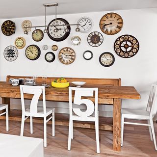 living room with white walls wooden flooring and dinning table with chairs clock on wall