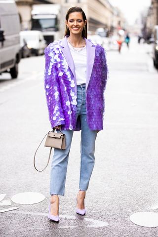 a woman wearing a purple sequin blazer with straight leg jeans
