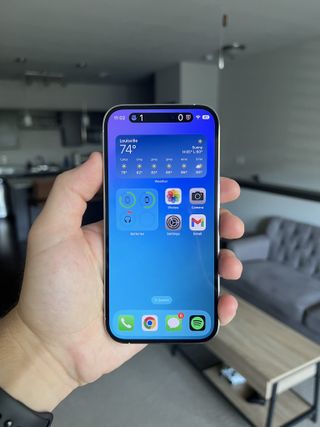 An iPhone 14 Pro with a blue wallpaper and the dynamic island producing live updates on the football score