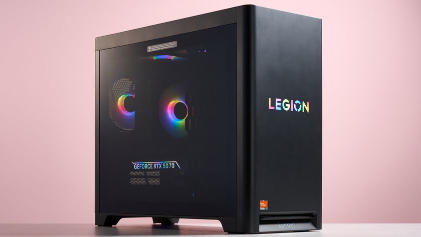 Three-quarter view of Lenovo Legion Tower 5 on desk with RGB lighting on, with pink wall in background 