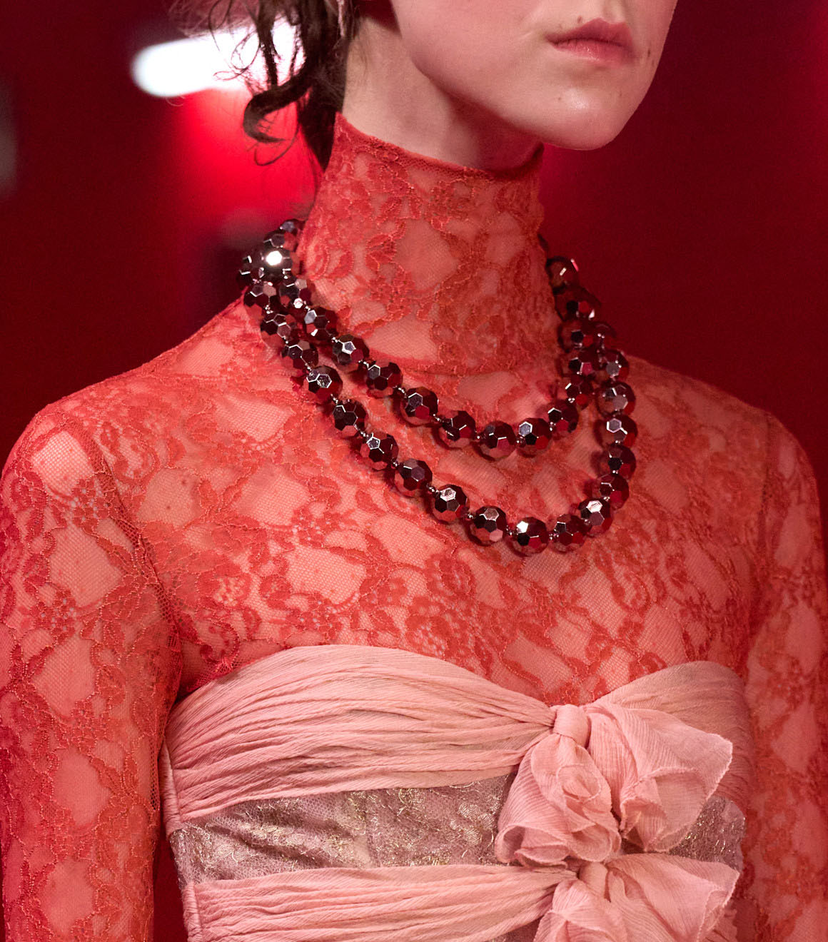 A Valentino model wearing a ruby toned beaded necklace.