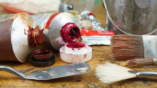 Some tubes of oil paint with brushes and a brushwasher