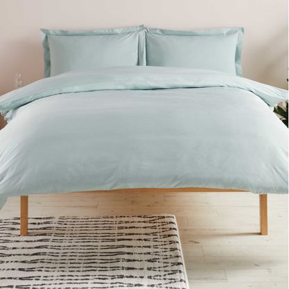 bedroom with black and white rug on wooden flooring with duck egg blue bedding and pillows