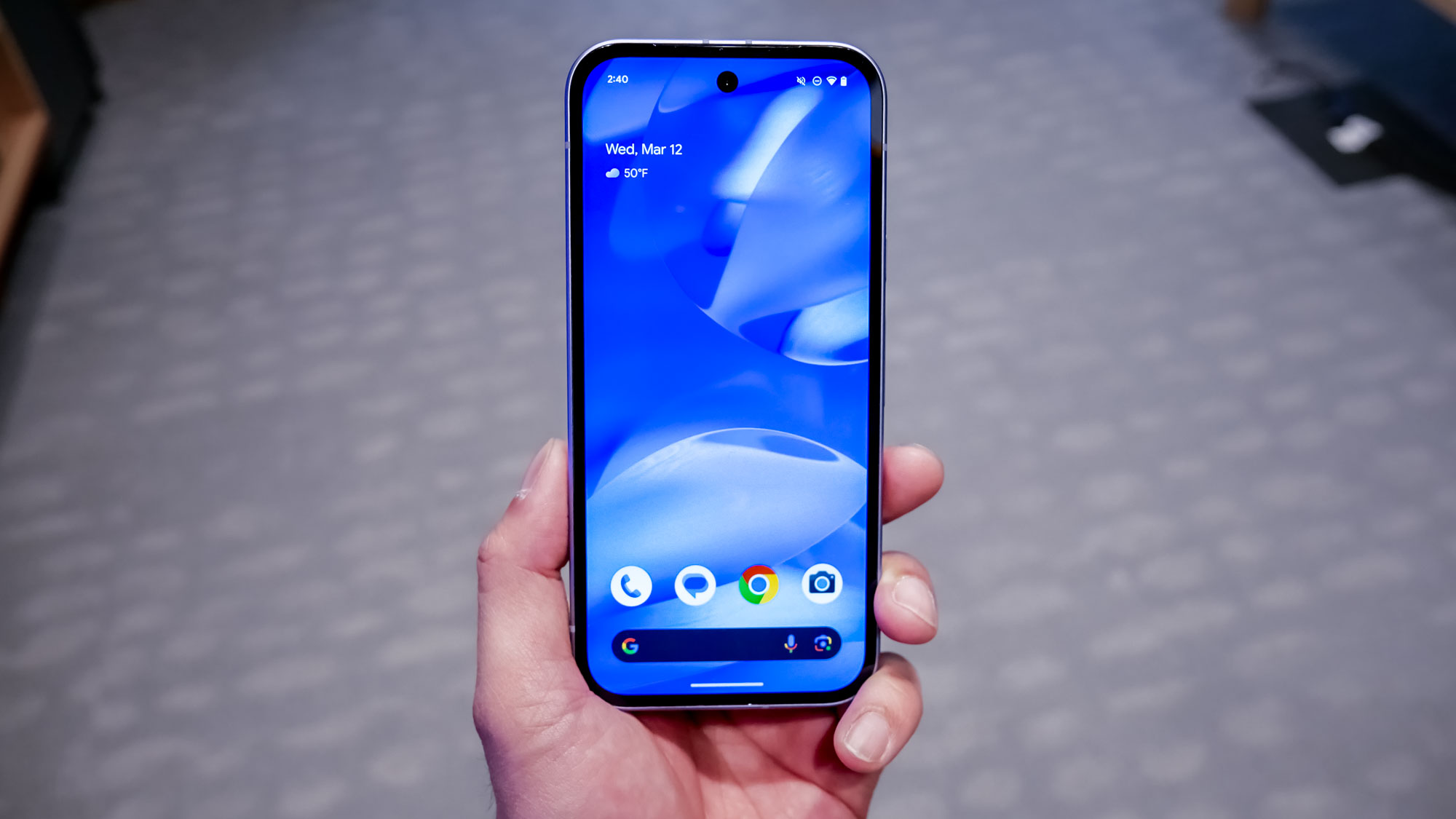 Google Pixel 9a held in the hand with display turned on.