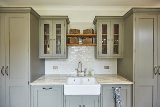 Utility room storage solutions showing symmetrical cabinets surrounding a small granite worktop with a Belfast sink