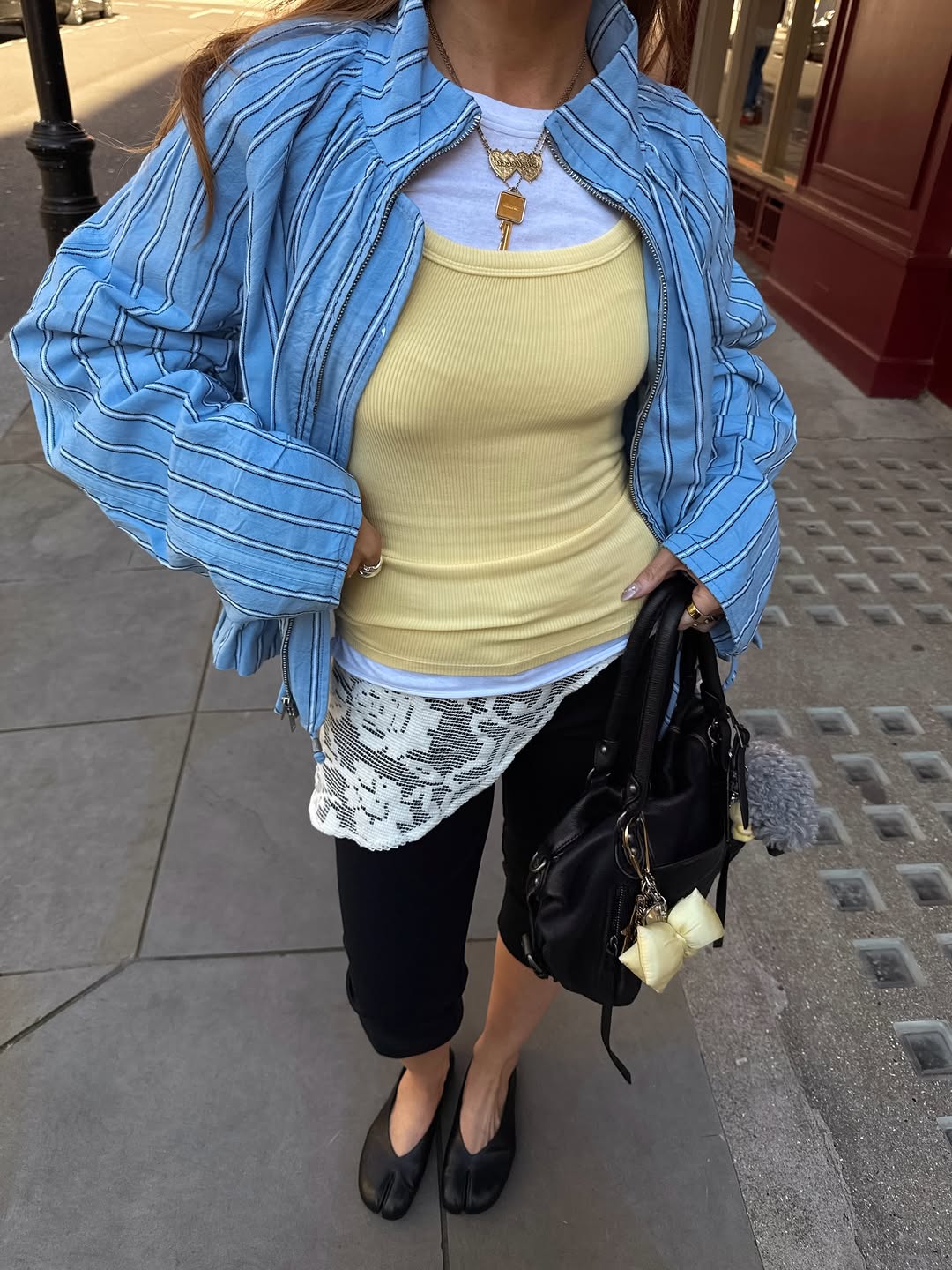 A woman wearing a layered tank, blue jacket and black capri, part of the Spring Basics outfits 2026.
