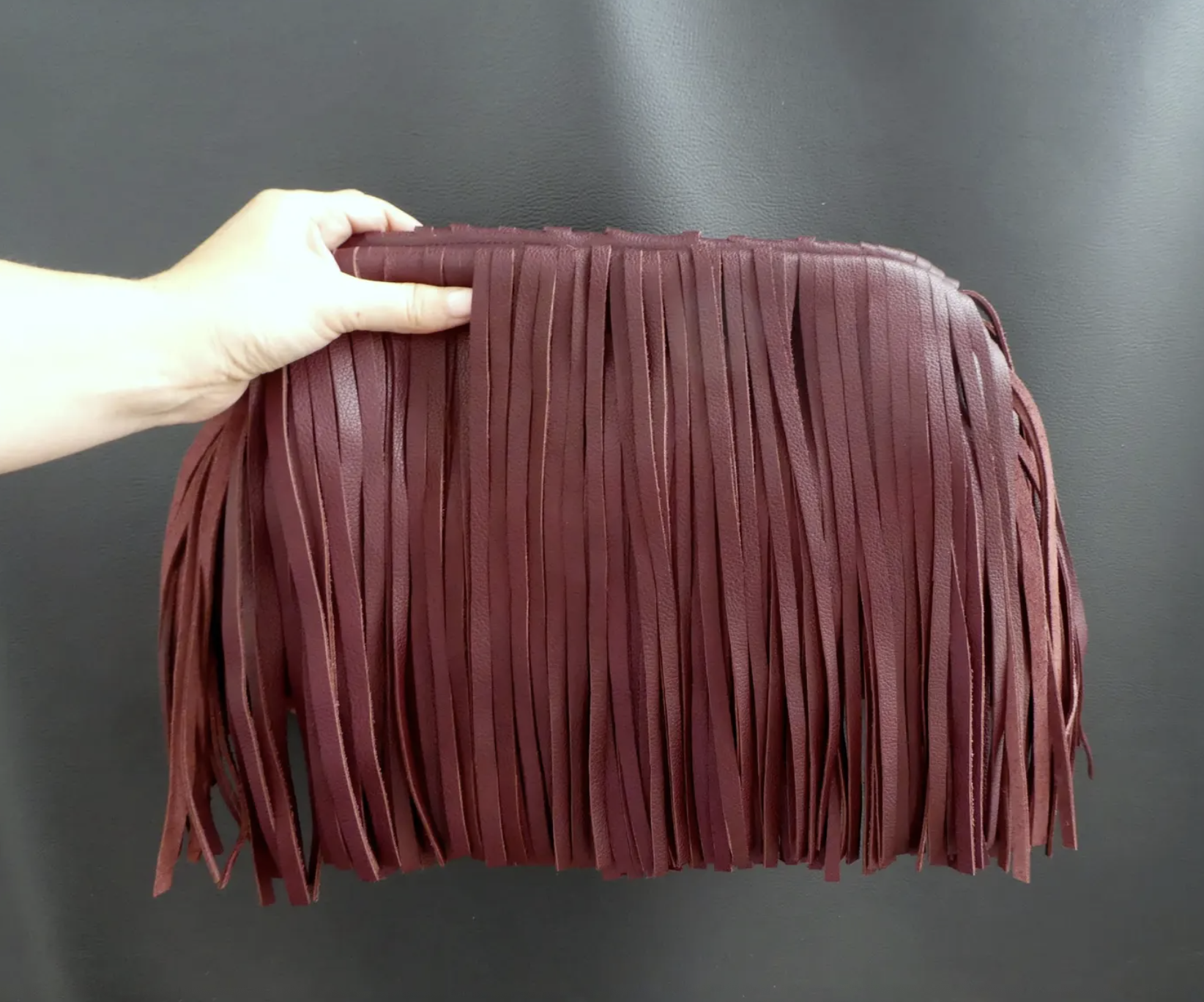 a model holding up a fringed clutch