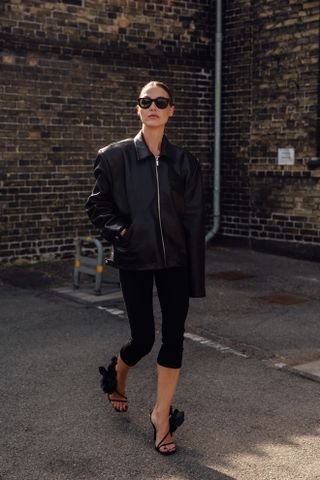 woman wearing leather jacket, capri pants, and heels