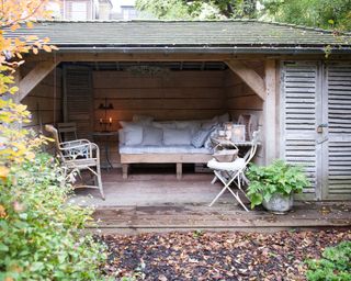A wooden open-sided pavilion with bench seating inside, acting as an idea for garden privacy.
