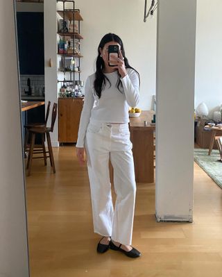 A fashion influencer in an all-white outfit with classic black ballet flats