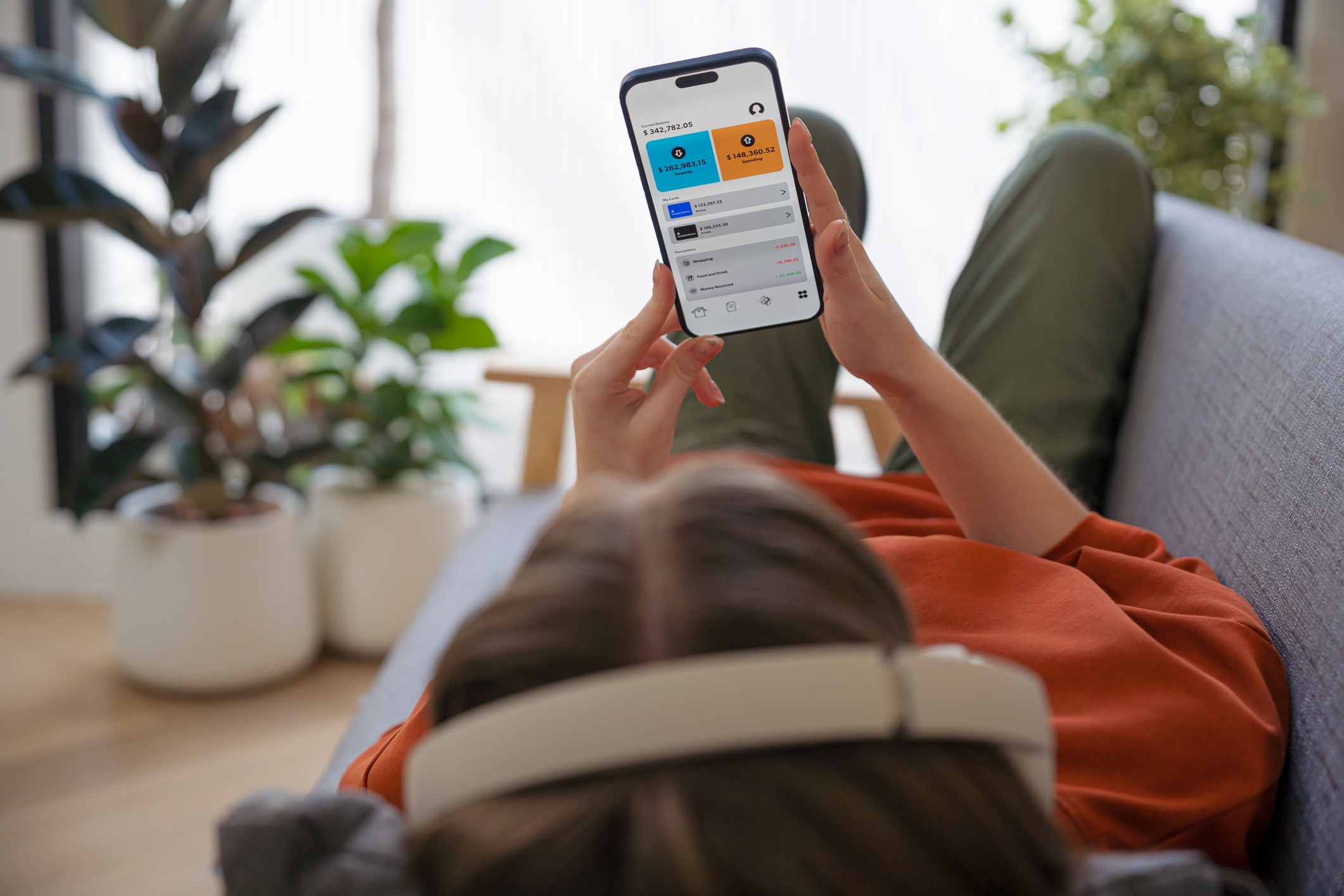 A young woman wearing headphones investing on her smartphone