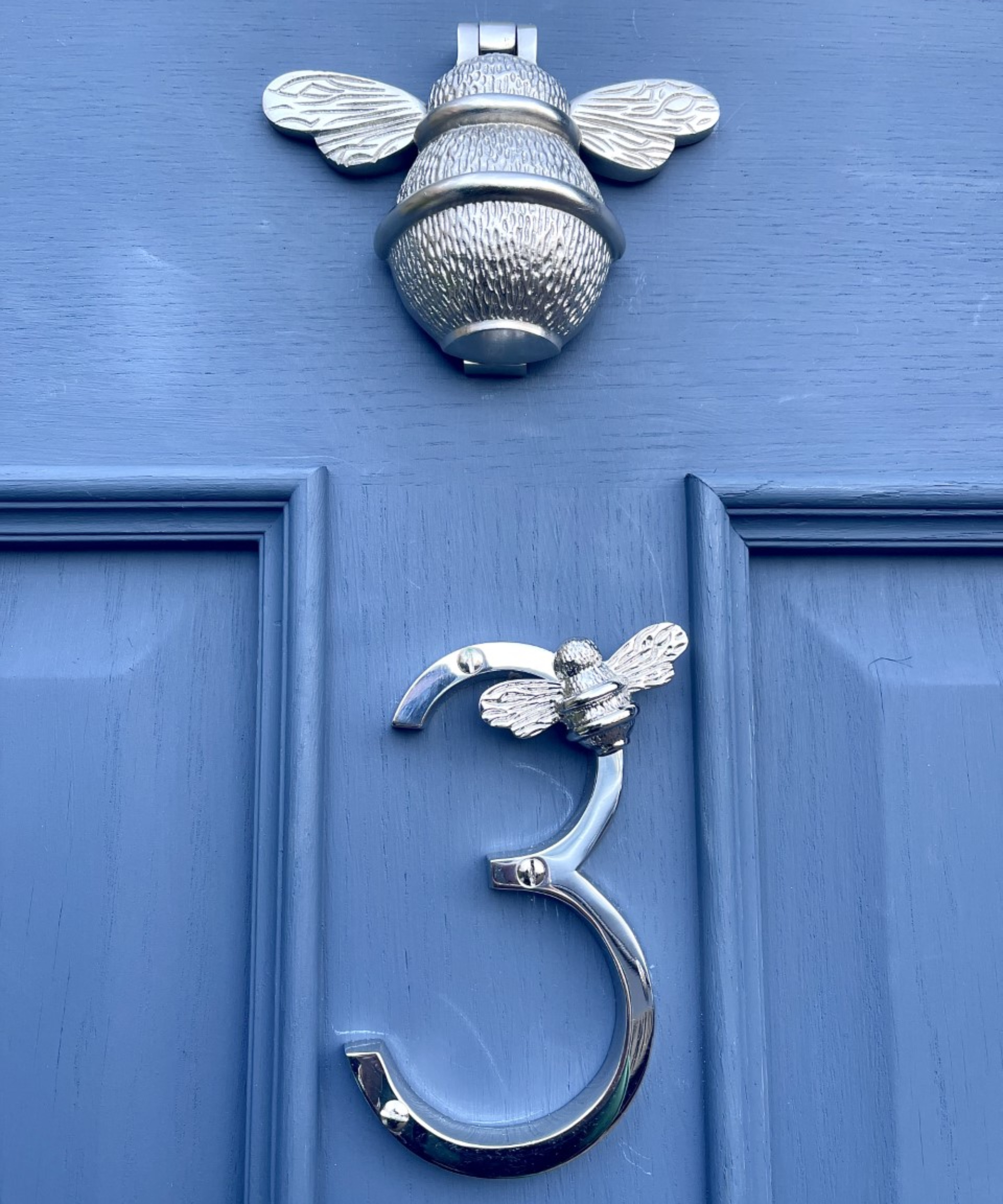 close-up of blue front door with silver bee knocker and silver number 3 with metal bee on side