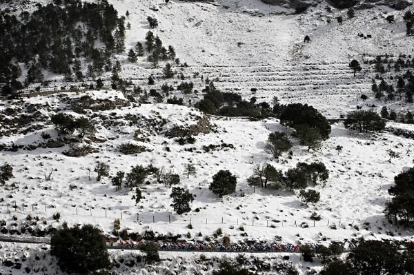 The peloton speeds past snow-covered hillsides