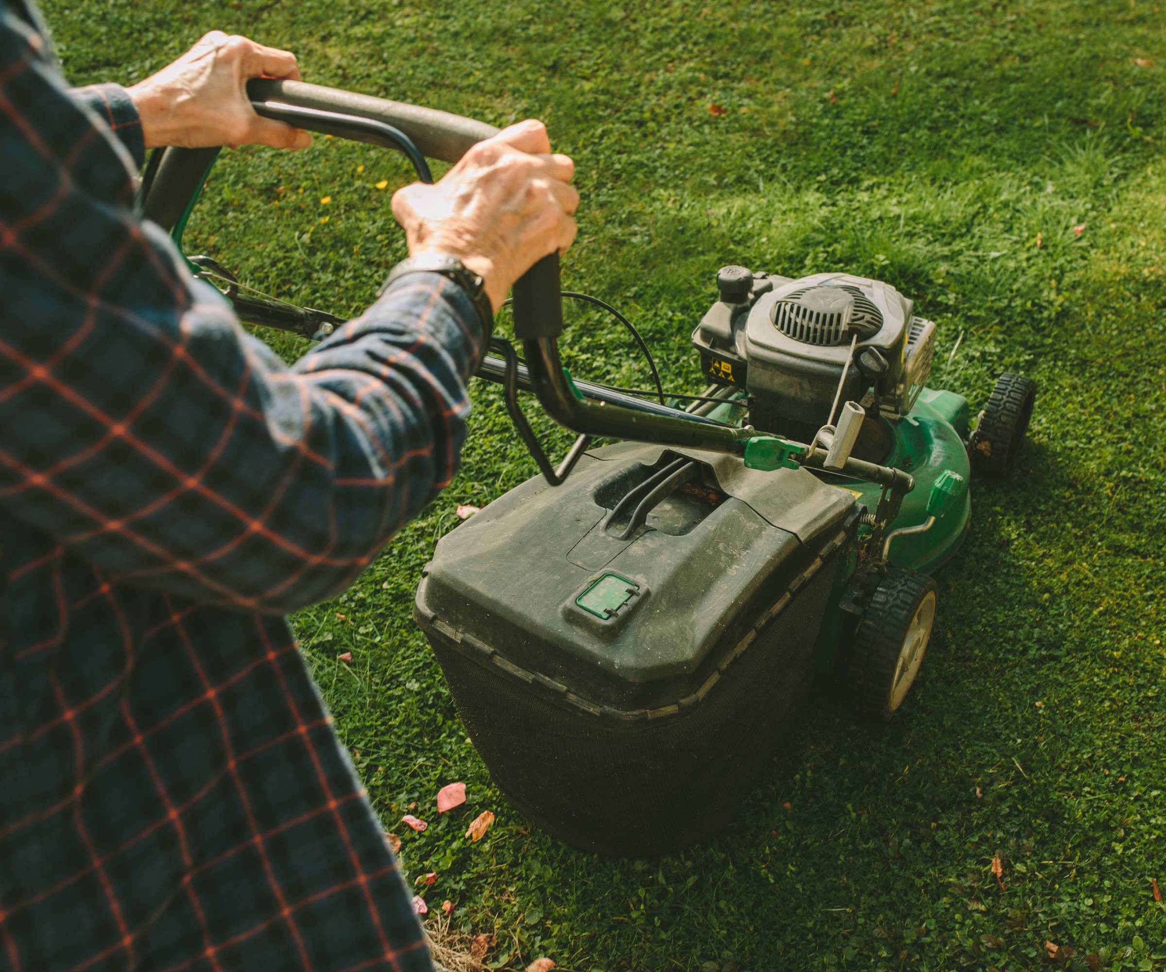 A man&#039;s hands pushing a lawn mower