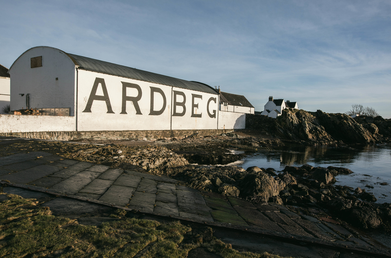 A white whisky distillery building next to the sea