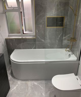 Gray marble effect bathroom with white tub and toilet