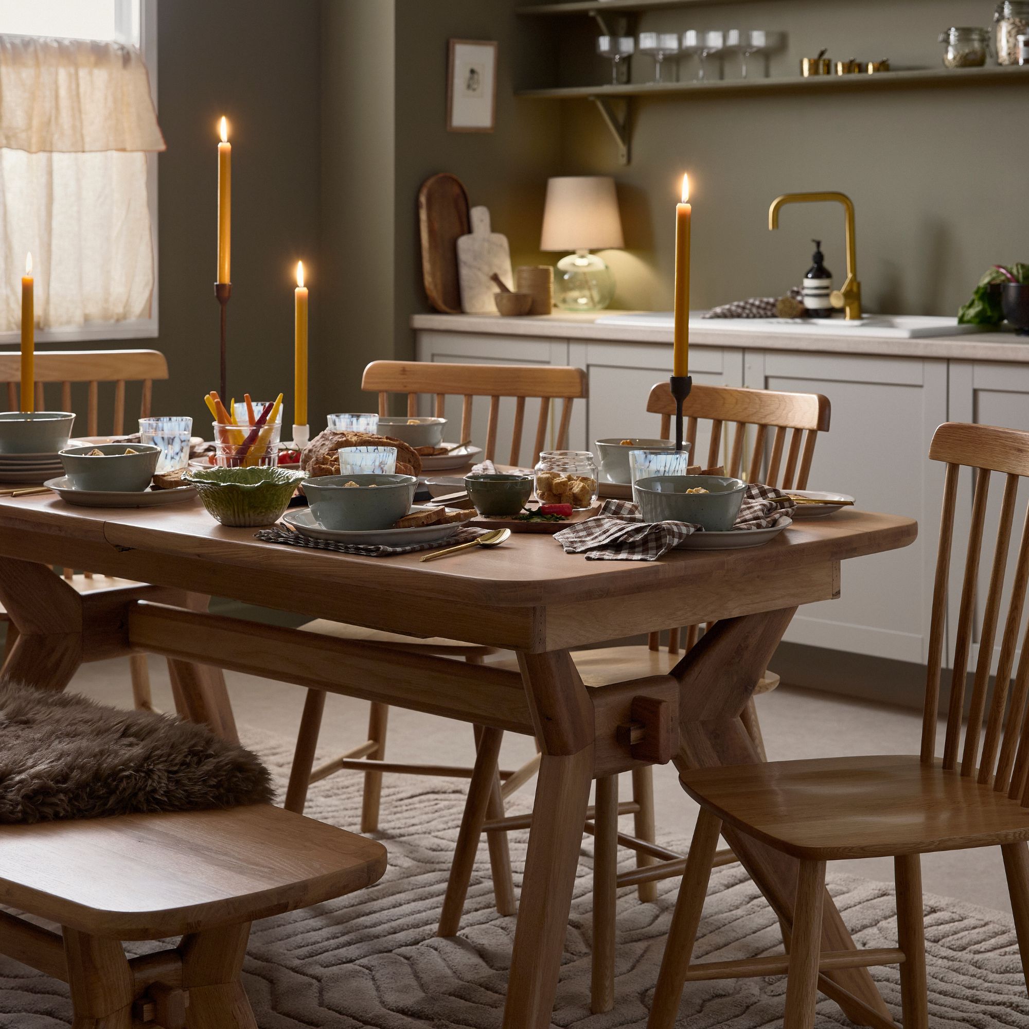 An oak dining table and chair set in a sage green dining room