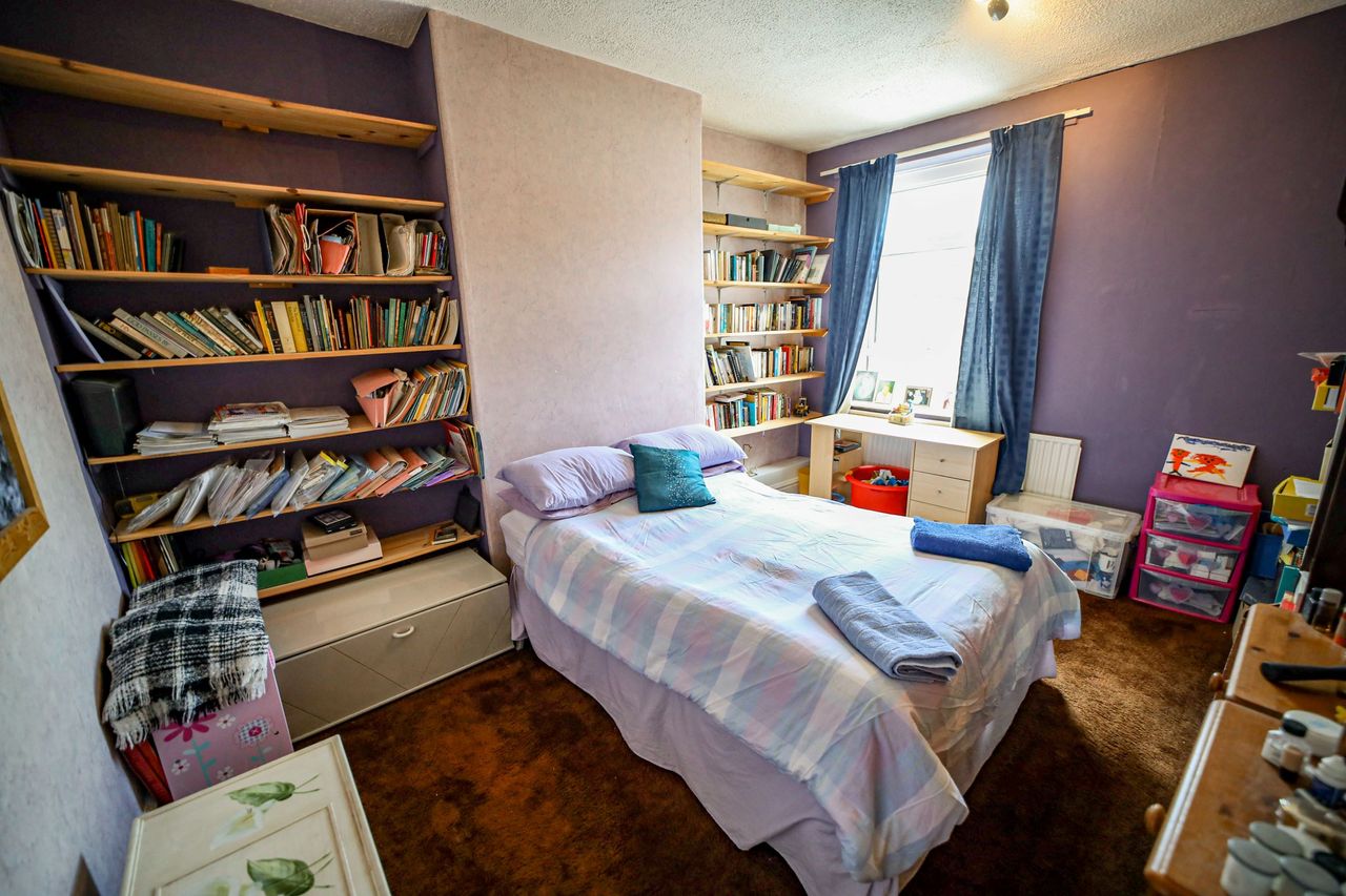 A bedroom with two large bookcase in built next to the bed which cover the entire wall