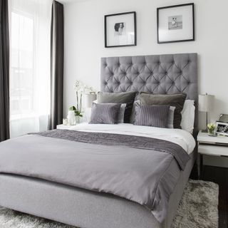 White bedroom with grey bed, sheets and upholstered headboard