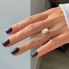A close-up of a short inky black manicure