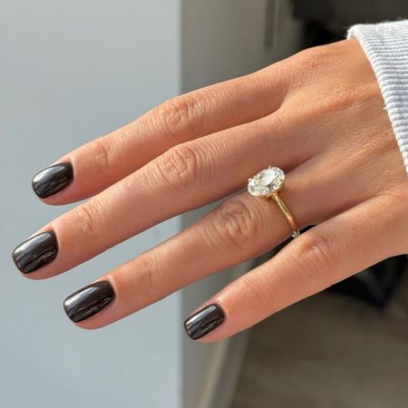 A close-up of a short inky black manicure