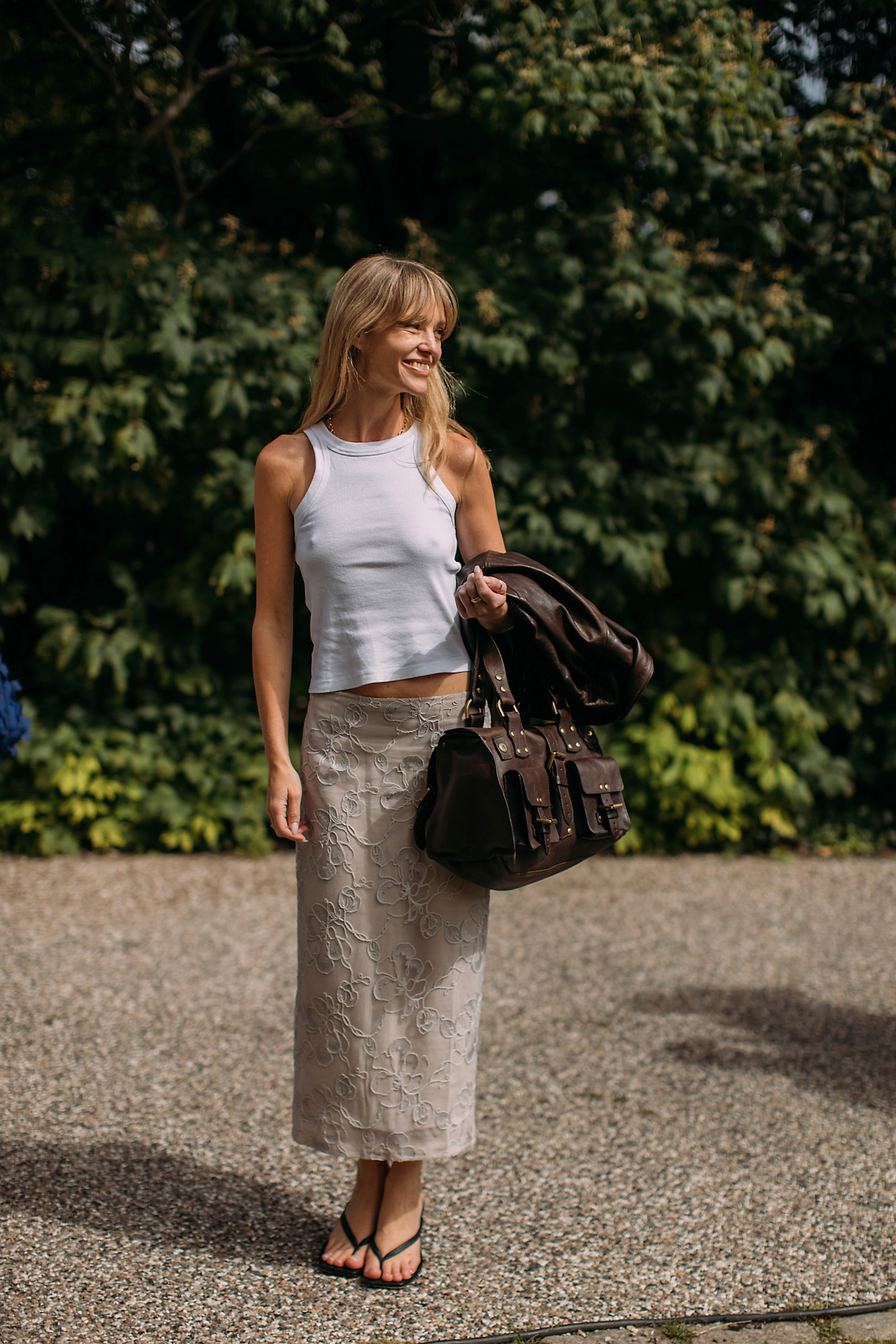 fashion week attendee wearing white tank top, skirt, and flip-flops