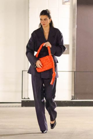 Kendall Jenner wears a matching suit, orange bottega bag, and the row pumps.