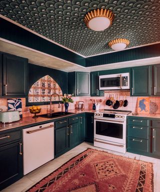 pink bohemian kitchen with scalloped emerald green ceiling design, art deco ceiling lights, green cabinets and pink copper counters