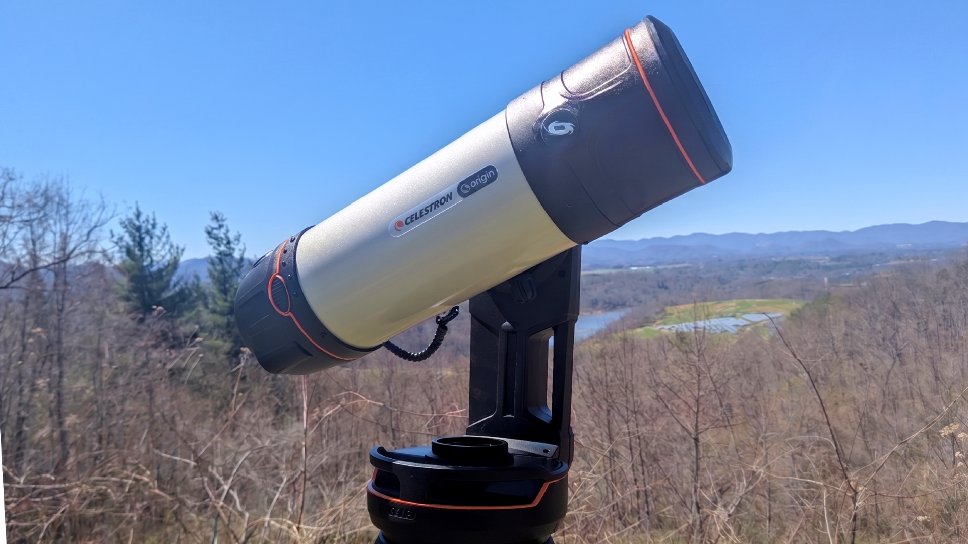 a white telescope on a grassy mountaintop under a clear blue sky