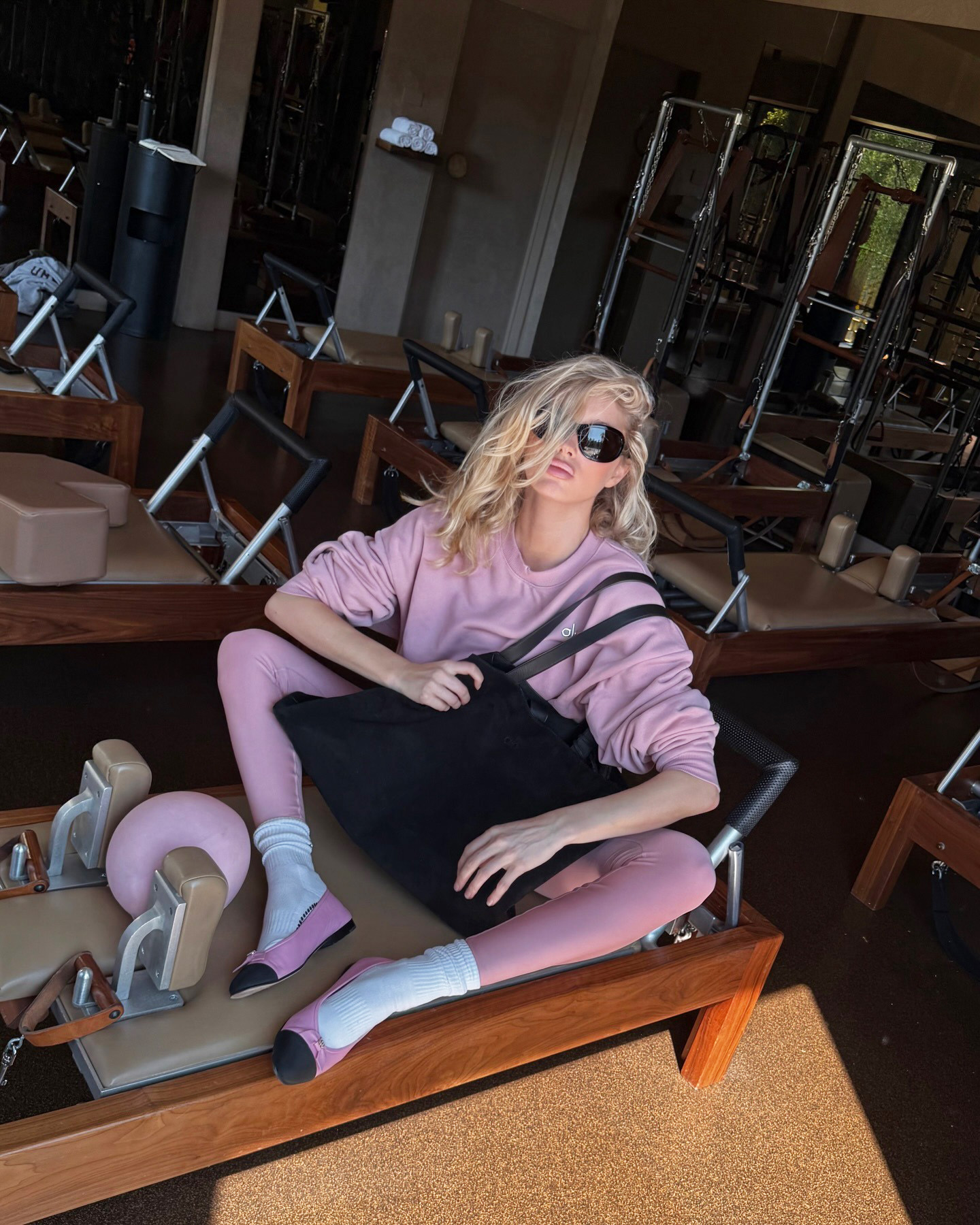 Elsa Hosk wearing Alo pink sweatshirt and leggings with a black Alo bag, white socks, and pink Chanel ballet flats