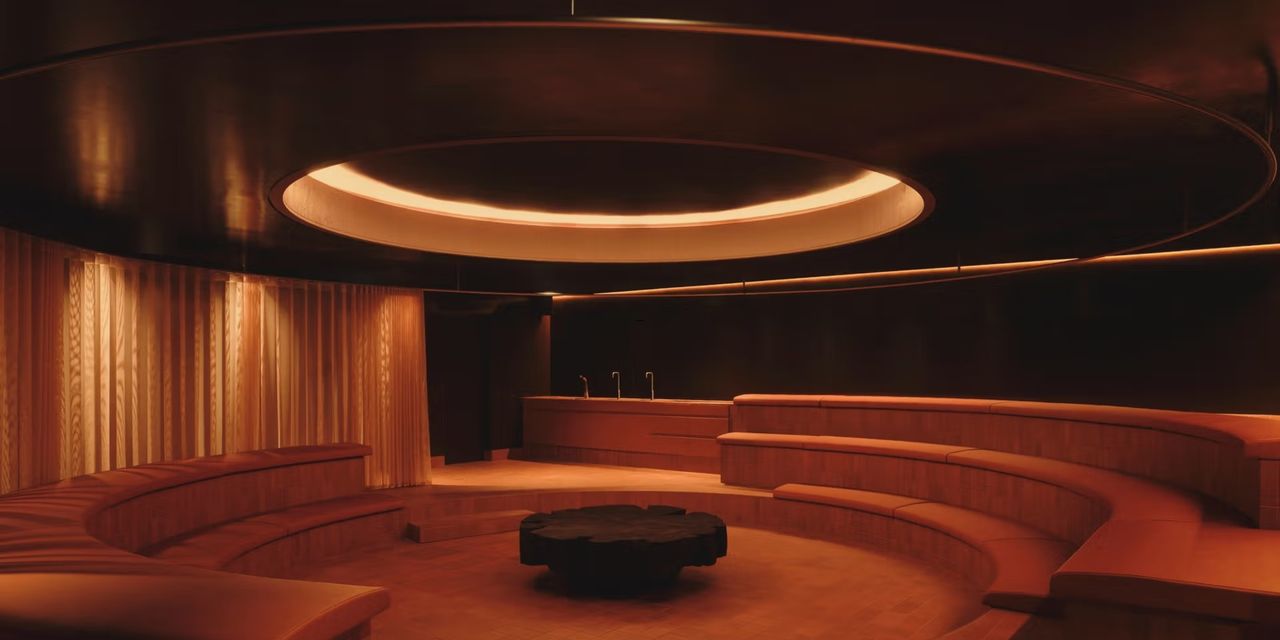 A futuristically designed sauna space features terracotta-drenched, concentric interiors punctuated by minimalist lines and softly glowing light.