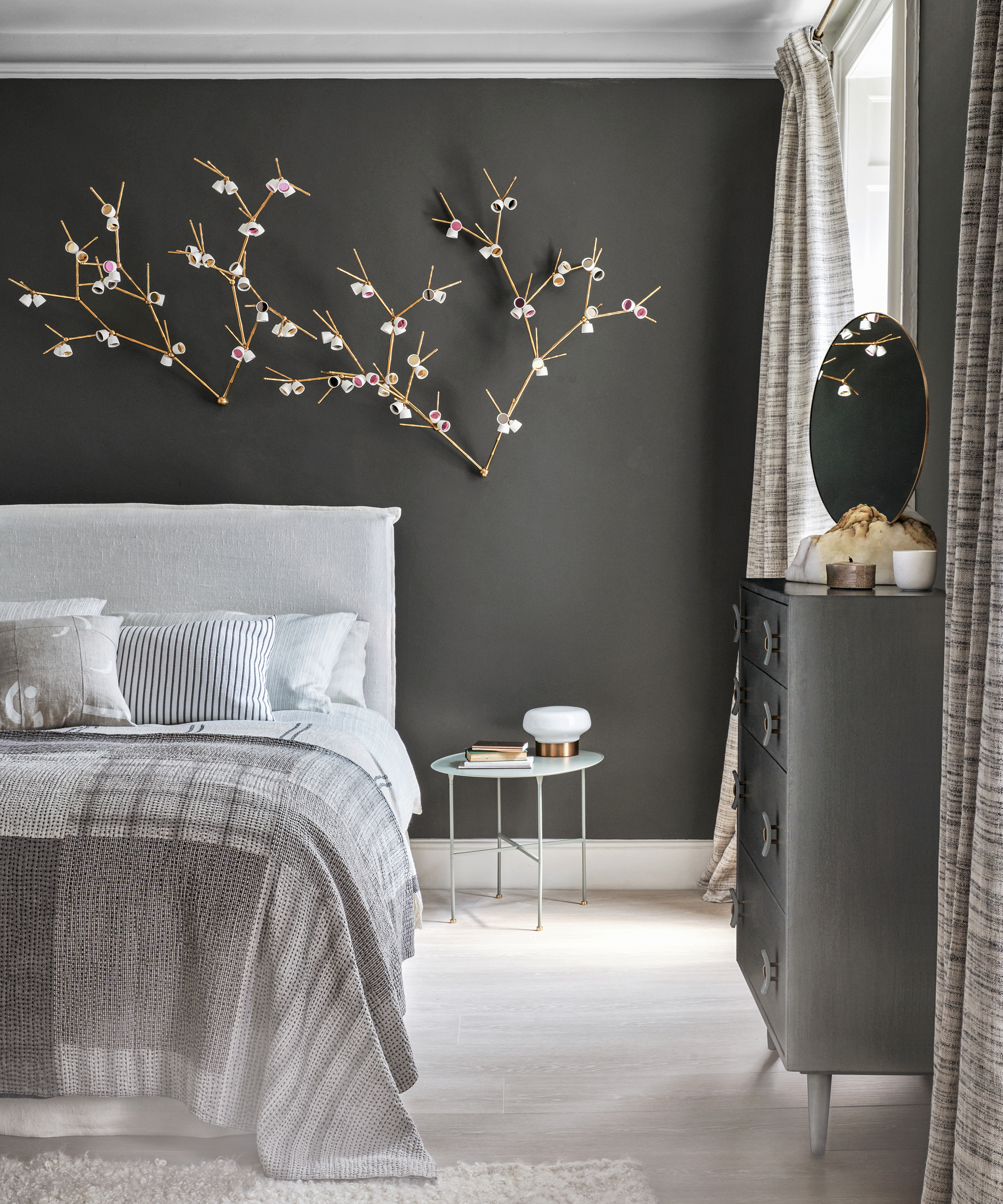 A grey bedroom idea with dark grey walls, a nature inspired light installation and grey wooden floors