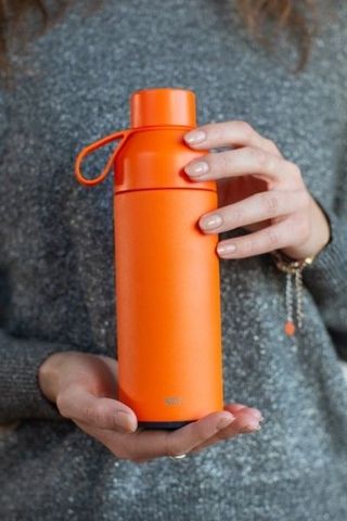 a woman holding Ocean Bottle in orange