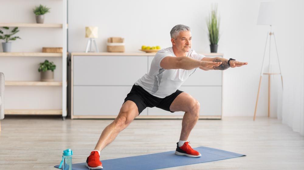 a man doing lateral lunges on an exercise mat at home