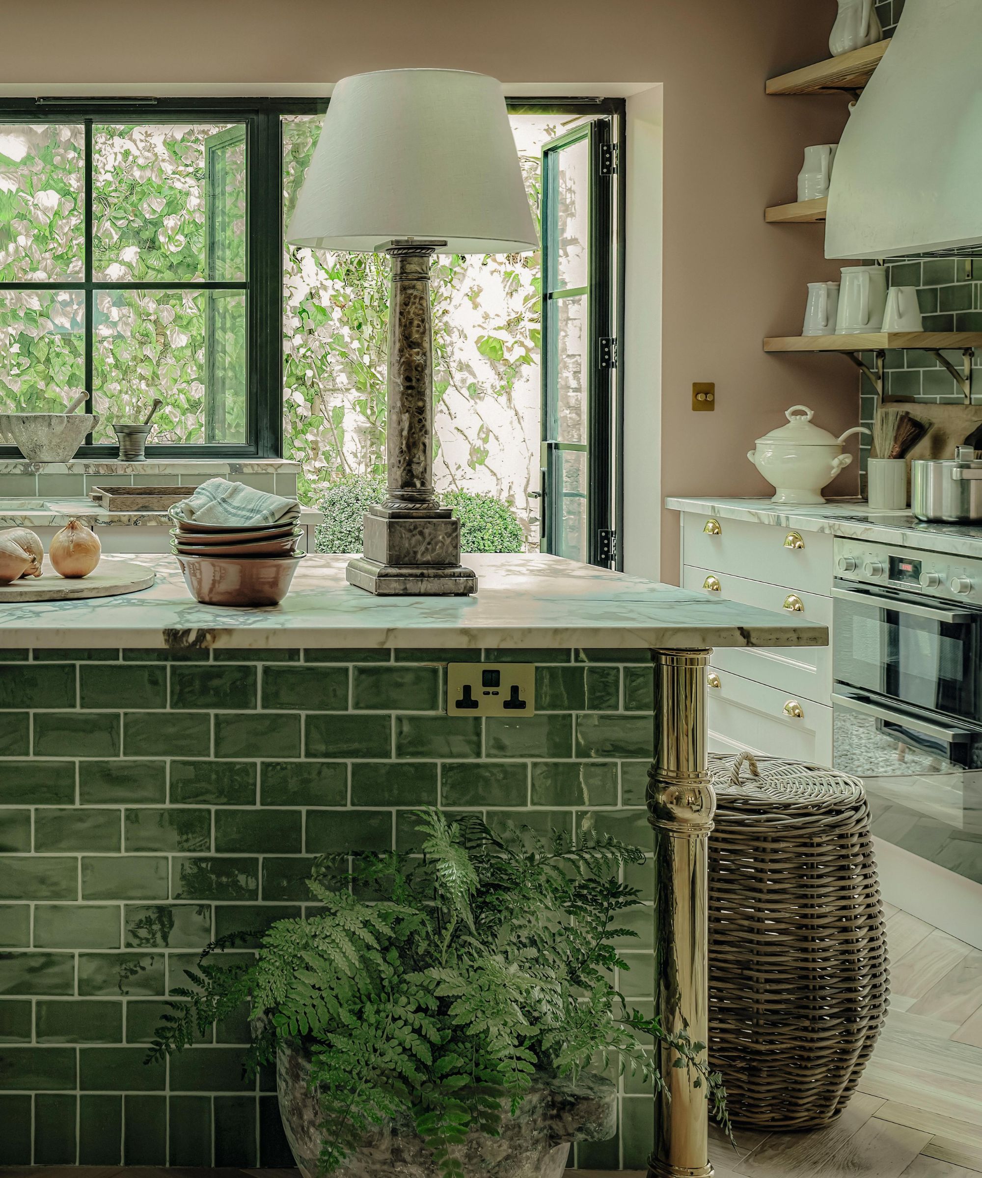 a large london kitchen with a large island clad with glossy green tiles and styled with a rustic lamp